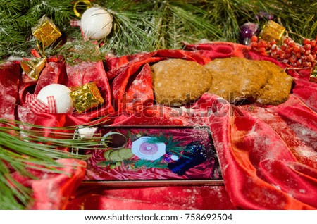 Smartphone lies on a red background with Christmas tree branches cookies with toys balls and gifts. Christmas New Year holiday