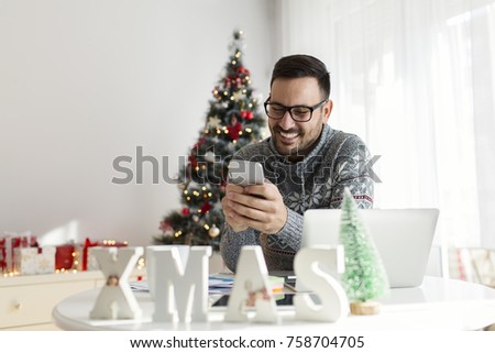 Handsome young man using phone at home for Christmas
