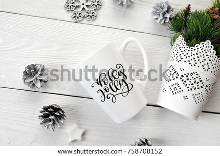 Christmas text Holly Jolly on a white mug with a christmas decor. Flat lay, top view photo mockup
