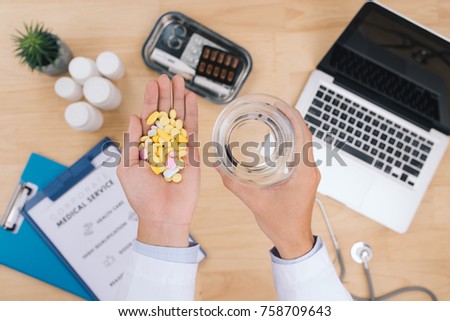Male doctor hand holding different colorful capsule. Medical treatment, antibiotics resistance problem and rational drug use concept. Selective focus.
