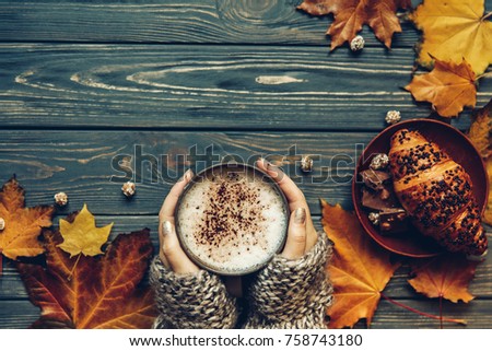 Cup of hot cappuchino coffee with chocolate croissant, Autumn mood, holding hands, top view , warm and cozy 