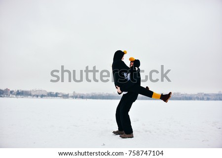 Young couple in the penguin costumes are have fun on snow.