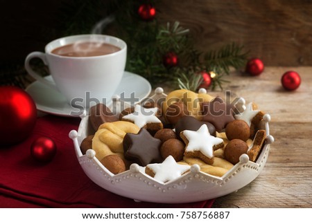 christmas cookies and a coffee cup with hot cocoa, fir tree branches and red baubles on rustic wood for a cozy advent afternoon, copy space, selected soft focus, narrow depth of field