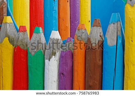 Large wooden coloured pencils as a fence outdoors