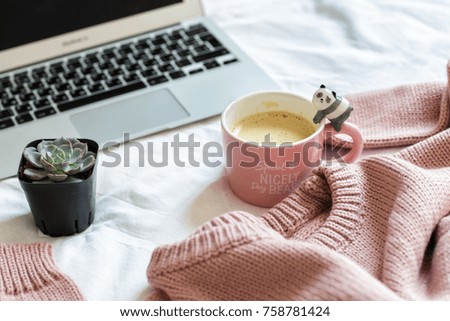pink knitted sweater, a cup of coffee, flower and a notebook lie on the bed in the bedroom