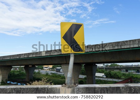 yellow curve warning sign on side of express high way