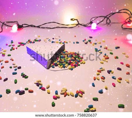 Christmas decoration triangle gift box with colorful candies with lights and snow for celebration best Christmas holidays background image for invitation