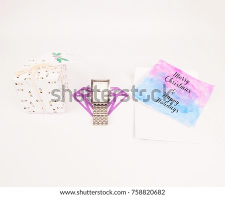Flat lay photo of Christmas decoration with opened square gift box with silver watch and greeting card for celebration best Christmas holidays background image for invitation