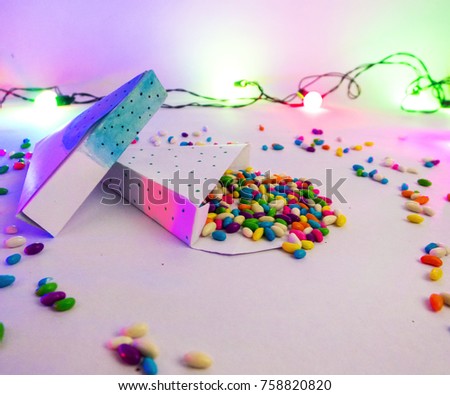 Christmas decoration triangle git boxes with colorful candies spread as confetti under party lights for celebration best Christmas holidays background image for invitation