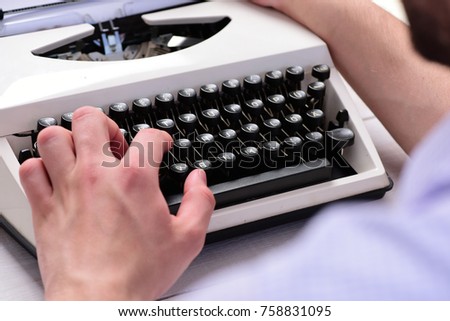 Writer typing with retro writing machine. Old typewriter and authors hands. Male hands type story or report using white vintage equipment on defocused background. Typography and writing concept.
