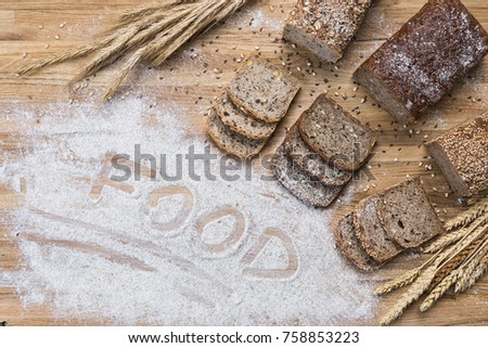Composition of whole grain bread on a wooden table with flour
