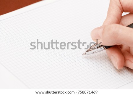 Female hand writes a pen in notebook