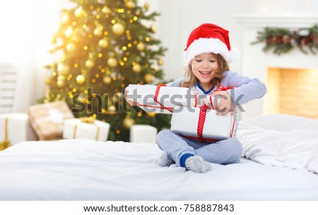 happy funny child girl  with gifts  in bed on Christmas morning
