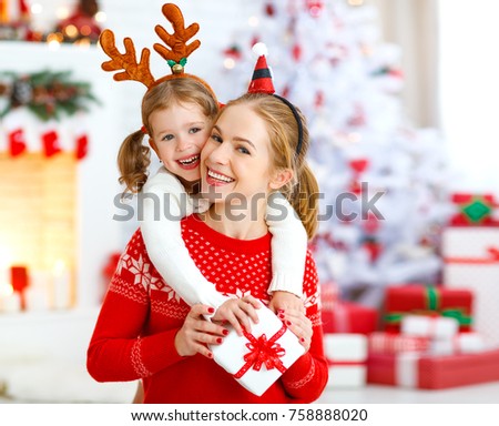 happy family mother and daughter giving christmas gift and embracing
