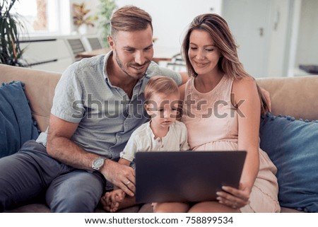 Mother, father and son sitting on sofa and watching cartoon.