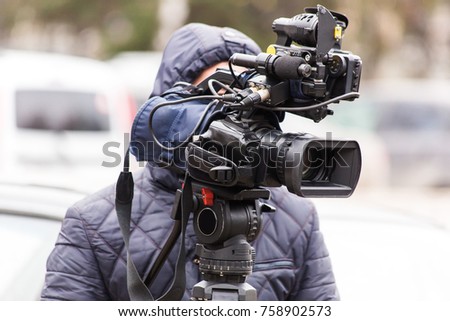The cameraman shoots a report on a professional video camera from a tripod. street report.