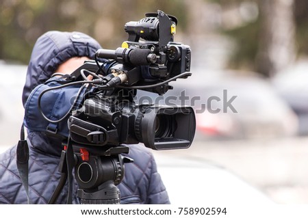 The cameraman shoots a report on a professional video camera from a tripod. street report.