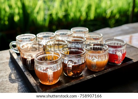 Coffee with multiple assorted types and flavors  tea in identical mugs for degustation on farm in Indonesia, Bali. Fruit and herb tea testing set. Selective focus.