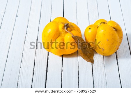 two quinces on white wooden background