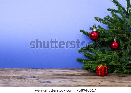 Wooden table and spruce branches with Christmas decorations on bright colored background. Studio Photo
