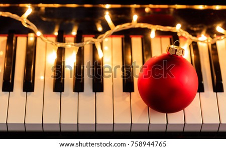 Christmas ball and lights on a classical piano keyboard, above view