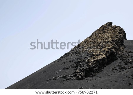 close up volcano crater with blue sky background. Black sand and rocks. 