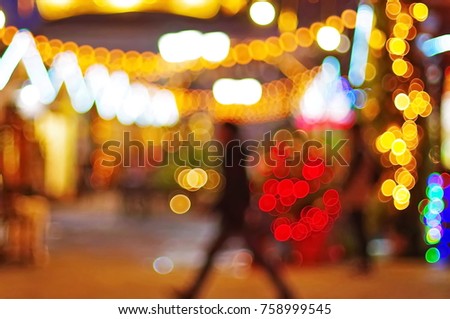 Silhouette of a walking man in the lights of a Christmas market, New Year's fair .Colorful bokeh  defocused Christmas fairy lights