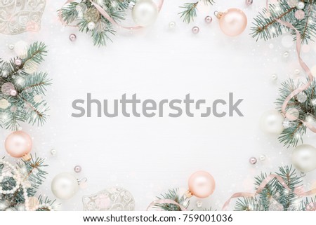 Holiday frame of Christmas decorations on white background with fir branch, pink balls, ribbon and pearls. Elegant New Year`s snowy card. Top view.