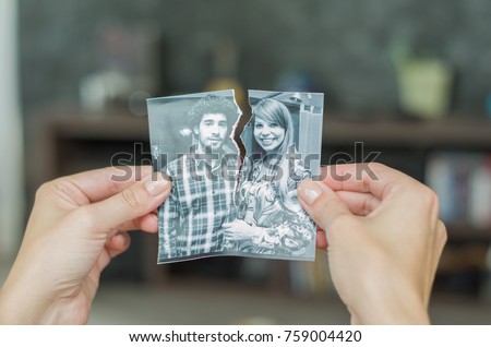 Great concept of divorce, betrayal, separation, woman hand ripping photo of the couple.
