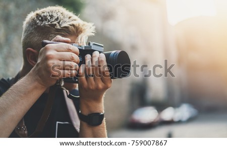 Young professional male videographer shooting outdoor on modern camera, empty area with copy space for your content, design or text message, flare light effect, man photographer taking photo outdoor