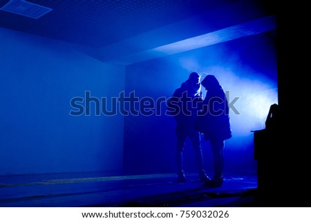 silhouette of a man and a woman standing in a tunnel in a smoke against a background of bright light. toned