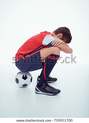 Photo of upset  teen boy in sportswear after soccer game - posing at studio