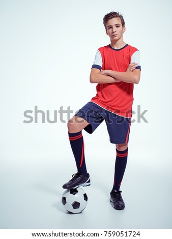 Photo of teen boy in sportswear holding soccer ball - posing at studio. Full portrait.