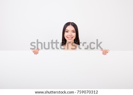 Copy space portrait of charming, attractive, cute girl hiding, standing behind empty white horizontal wall isolated over white background