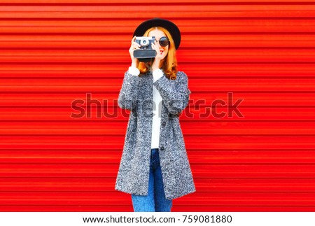 Fashion portrait pretty woman with retro camera on a red background