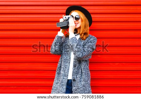 Fashion portrait smiling woman holds retro camera on a red background