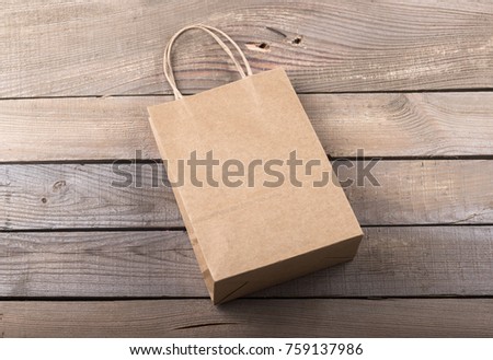Photo of craft paper bag. Template for branding identity isolated on old wood background.