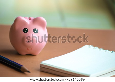 Pork piggy bank with notepad on blurry background for happy new year image. And welcome new year photo.