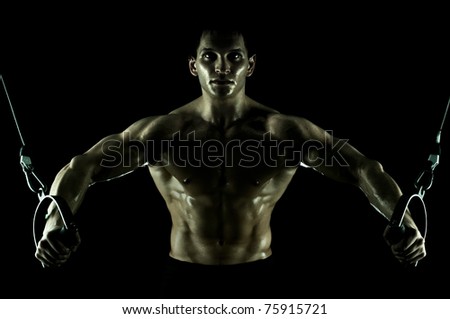 very power athletic guy ,  execute exercise on  on sport-apparatus, in  sport-hall, on black background, isolated
