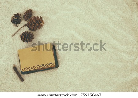 Empty note and pine cones over cozy and warm fur carpet. Scandinavian style design. Top view