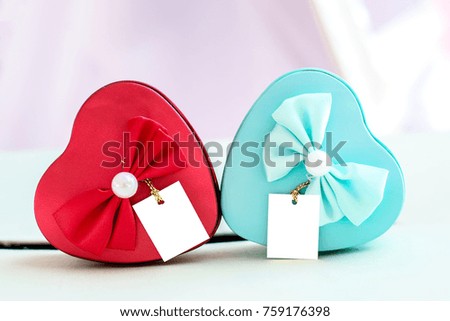 Blue and red heart box decorated with bow and pearls placed on the table.