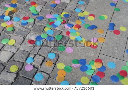 Paved street full of big round and colorful confettis after a festival