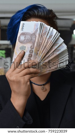 Face is covered with hand hold banknotes