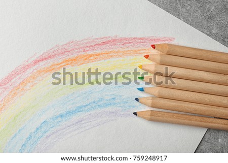 Beautiful drawing of rainbow and color pencils on grey background, closeup