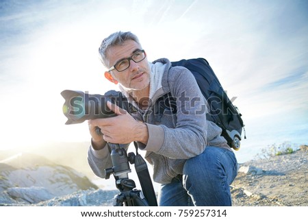 Portrait of photographer taking pictures in natural landscape