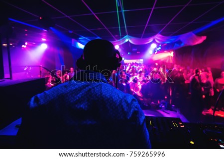 silhouette of DJ from back in headphones playing in nightclub