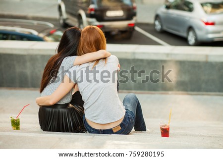 two girls hugging and drink cocktails, pretty friends, nice girlfriends walk around the city and drink lemonade. back view Royalty-Free Stock Photo #759280195