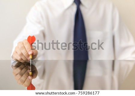 Businessman holding a dart  - business targeting, aiming, focus concept.