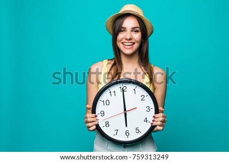 Young happy woman holding a clock with 12 clock on a green