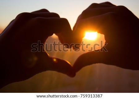 hands in heartshape on a background of a sunset